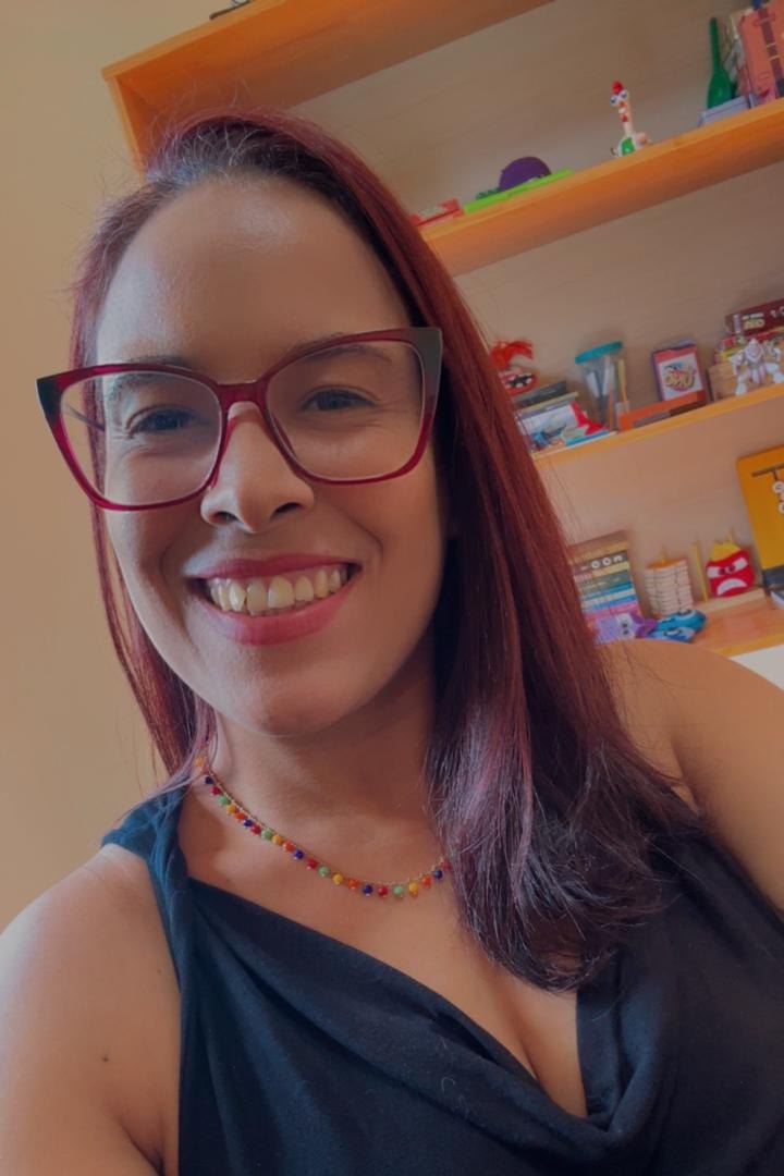 Psicóloga Camila Santos sorrindo no consultório