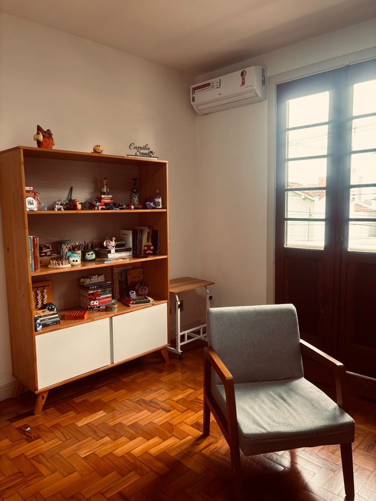 Consultório da psicóloga Camila Santos, com estante de livros e brinquedos e poltrona